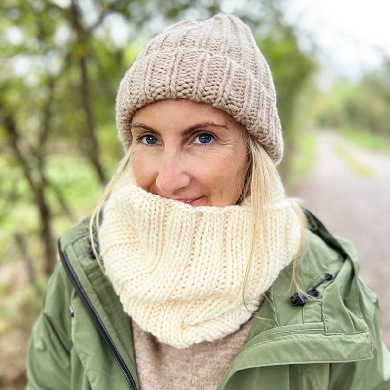 Woman wearing a beige knit beanie and scarf outdoors