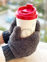 grey knitted mittens holding a coffee cup
